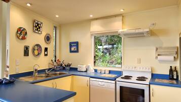 A compact kitchen with a blue countertop, white appliances, and various decorative plates on the wall.