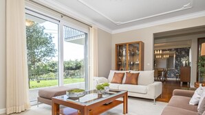 A modern living room with a glass coffee table, a sofa, and a dining area visible through a glass door. - Casa Olimpo by Homie (Camara de Lobos)