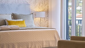 A neatly made bed with a white duvet and pillows, a bedside lamp, and a view of a balcony with a railing. - Casa Olimpo by Homie (Camara de Lobos)