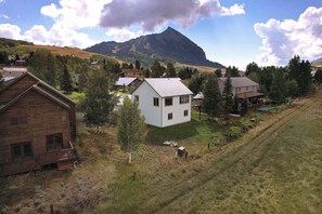 Un paysage rural avec une montagne imposante en arrière-plan, entourée de maisons aux toits de différents styles.