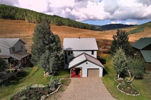 Ein zweigeschossiges Haus mit Garage, umgeben von einem gepflegten Rasen und Bäumen.