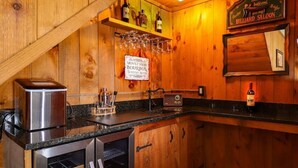 A wooden interior with a kitchen area, a sign for 'Mount Snow Bourbon Tastings Room', and a billiard table.