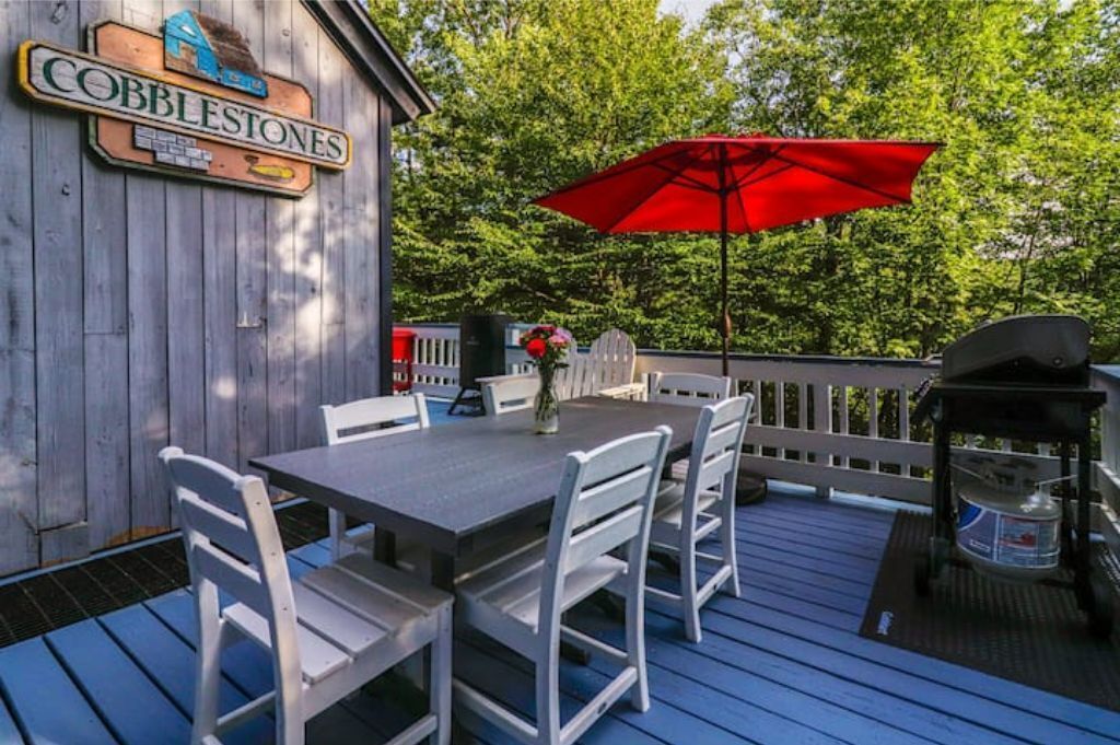 An outdoor deck with a table and chairs, a red umbrella, and a sign that reads "Cobblestones."
