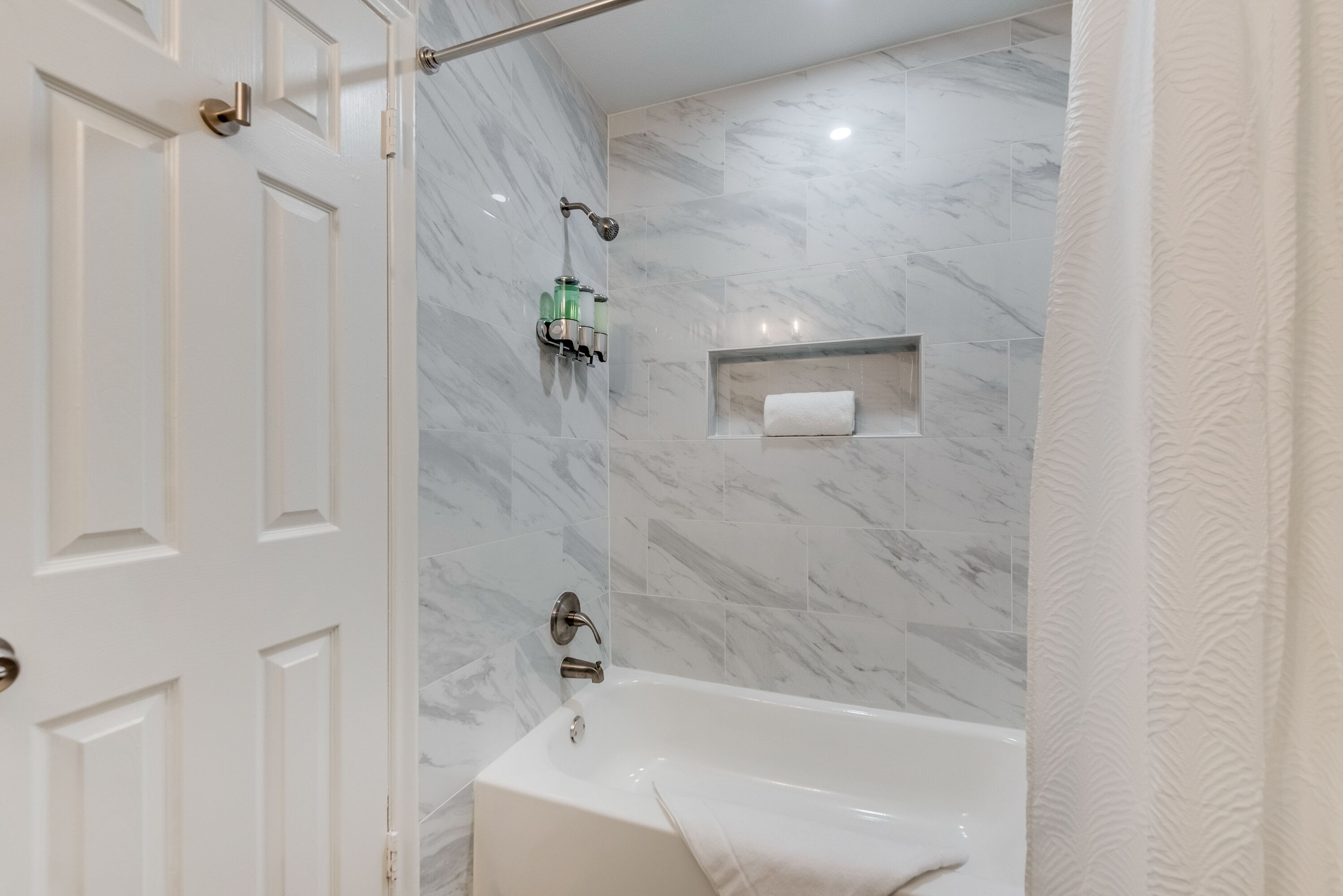 Un baño con bañera, cabezal de ducha y toallero.