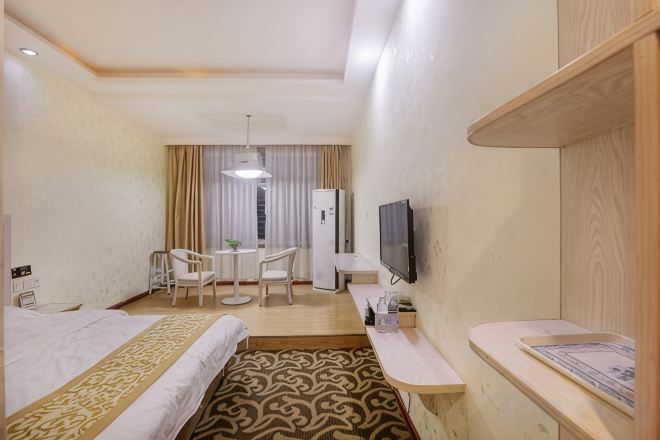 A hotel room with two beds, a desk, a chair, a television, and a view of the outside.