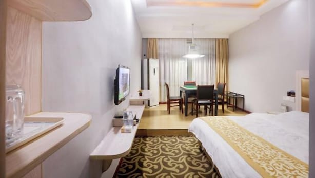 Een hotelkamer met een bed, een bureau, een stoel, een televisie en een raam met gordijnen.