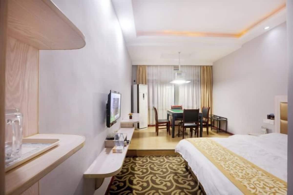 Une chambre d’hôtel équipée d’un lit, d’un bureau, d’une chaise, d’une télévision et d’une fenêtre avec des rideaux.