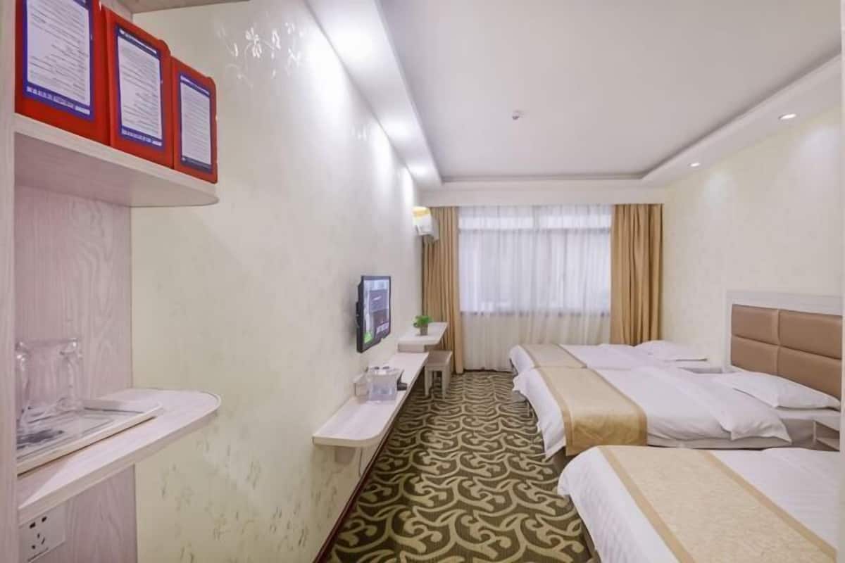 Une chambre d’hôtel avec un lit, un bureau, une télévision et une fenêtre avec des rideaux.