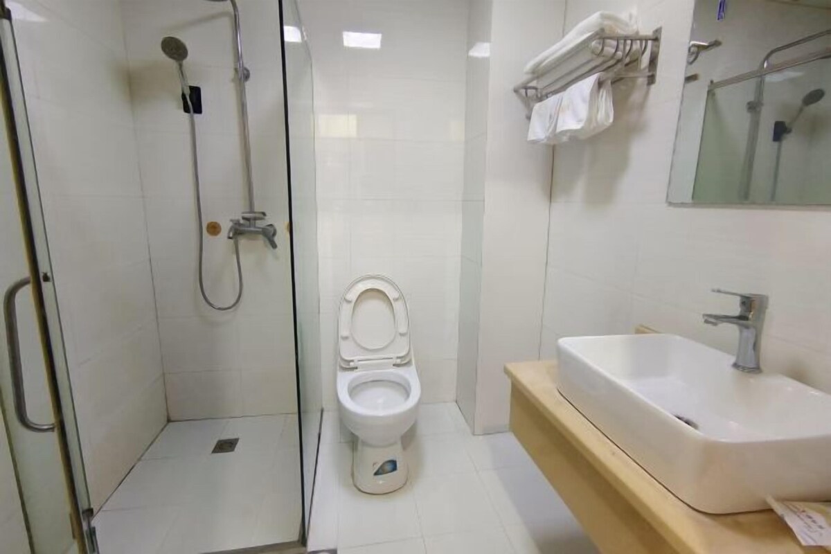 Een badkamer met een douche met glazen wand, een wit toilet en een wastafel met spiegel erboven.