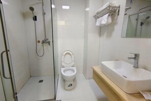 Een badkamer met een douche met glazen wand, een wit toilet en een wastafel met spiegel erboven.