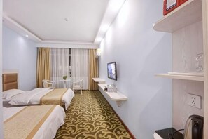 Een hotelkamer met twee bedden, een bureau, een stoel, een televisie en een koffieapparaat.
