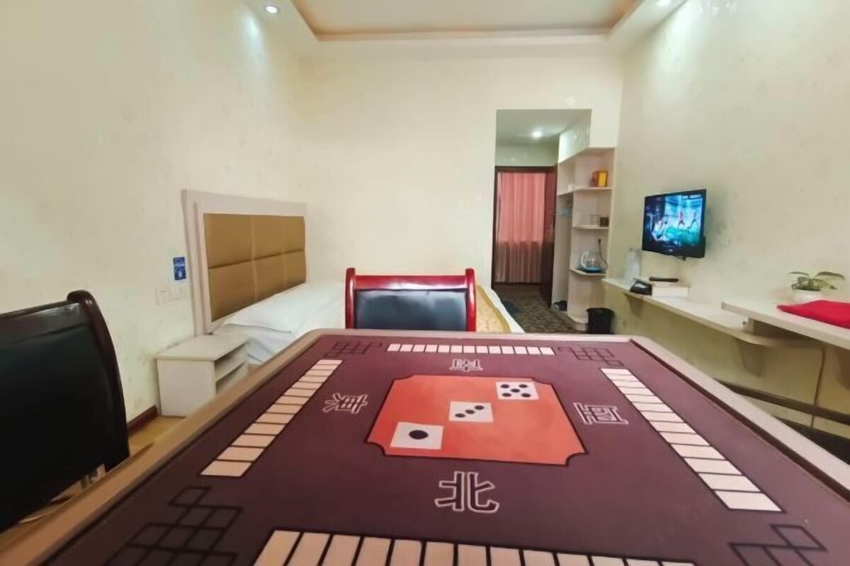 Een hotelkamer met een bed, een bureau, een televisie en een tafel met een spelbord.