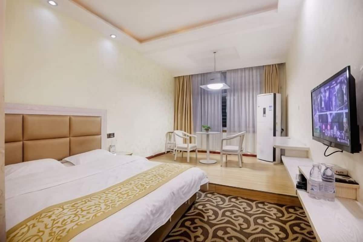 Une chambre d’hôtel équipée d’un lit, d’un bureau, d’une télévision et d’un petit coin salon.