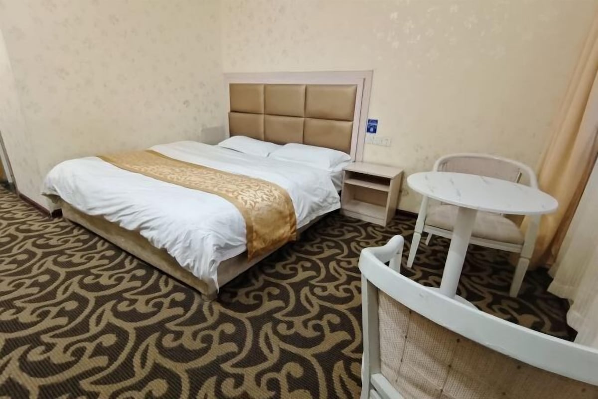 Een hotelkamer met een bed, een tafeltje en een stoel.