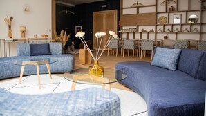 Un salon moderne avec un canapé bleu, une table basse en verre et une table d’appoint en bois.
