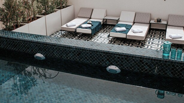 Un espace piscine aménagé sur le toit, avec des chaises longues et une piscine carrelée.
