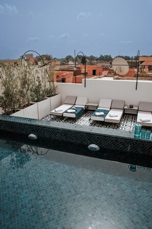 Zona d'una piscina al terrat, amb gandules i una piscina enrajolada.