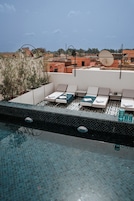 Un área de piscina en la azotea con sillas de descanso y una piscina con azulejos.