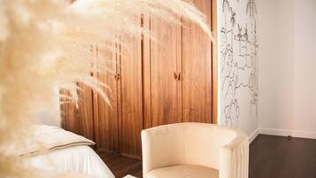 Un dormitorio con un armario de madera, una silla blanca y una pared con un mural floral.