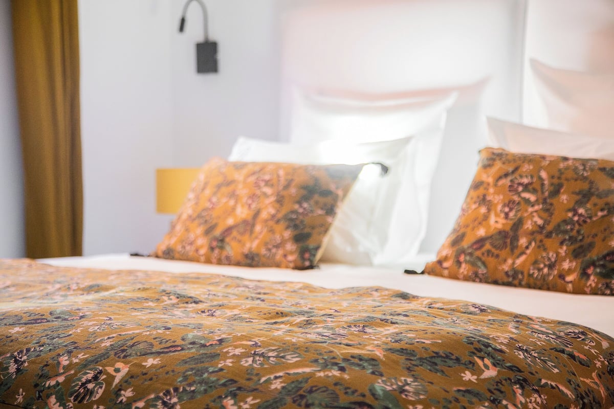 Una cama con ropa de cama floral y un dosel blanco.
