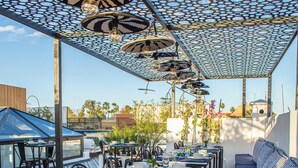 Un espace extérieur aménagé pour les repas, avec des tables, des chaises et un sol à motifs.
