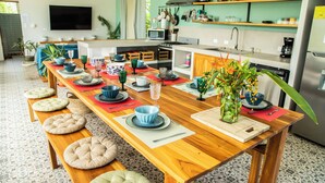 A modern kitchen with a wooden dining table set for six, equipped with various kitchen appliances and utensils. - NEW! Stylish, Luxury Jungle Retreat with Saltwater Pool Samara Beach 5 mins (Sámara)