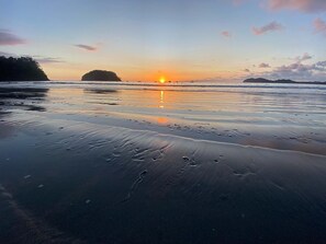 A beach at sunset with calm waters reflecting the sky.