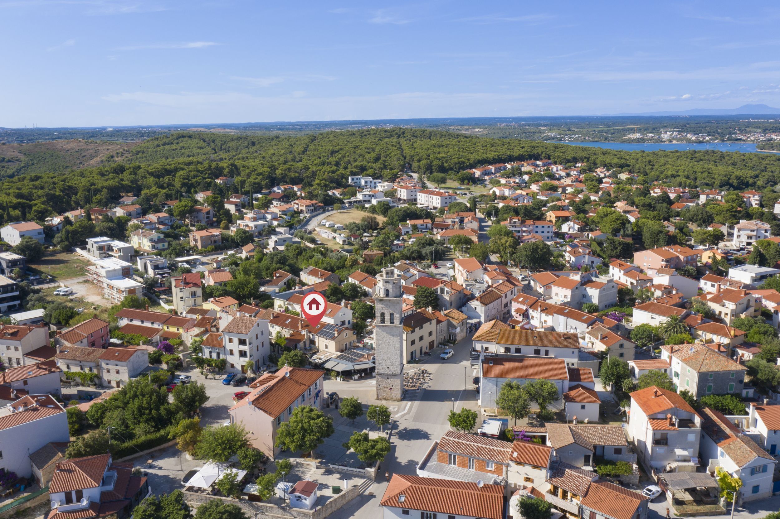 Une ville dotée d’une place centrale, bordée d’immeubles d’habitation aux toits recouverts de tuiles rouges, et sur laquelle se dresse une tour imposante.