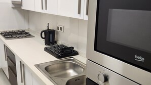 A modern kitchen with white cabinets, stainless steel appliances, and a black coffee maker. - Superb Urban Oasis in Almadies
 (Dakar)