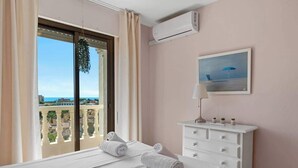 A hotel room with a balcony, a bed with towels, a white dresser, and a painting. - Zeus Apartment Riviera del Sol by Costarentals - Ref 221 (Mijas)