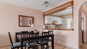 A dining area with a rectangular table and six chairs, a wall-mounted mirror, and a kitchen visible through an open doorway. - Zeus Apartment Riviera del Sol by Costarentals - Ref 221 (Mijas)
