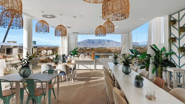 A modern dining area with a view of mountains, featuring wicker pendant lights, white furniture, and potted plants. - Casa Banderas Pool & Gym by Costarentals - Ref 237 (La Cala de Mijas)