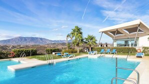 A swimming pool with lounge chairs and a modern building in the background. - Casa Banderas Pool & Gym by Costarentals - Ref 237 (La Cala de Mijas)