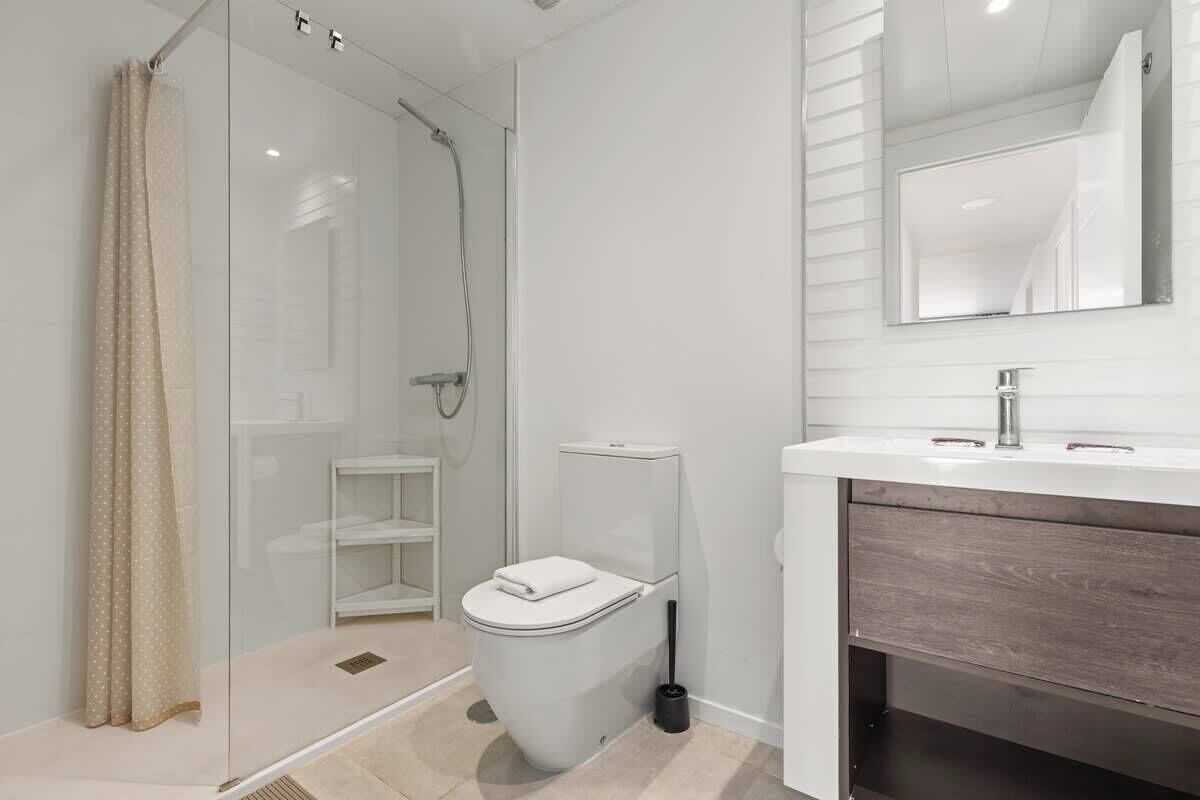 Une salle de bain moderne avec une douche à parois de verre, des toilettes et un meuble-lavabo avec un miroir.