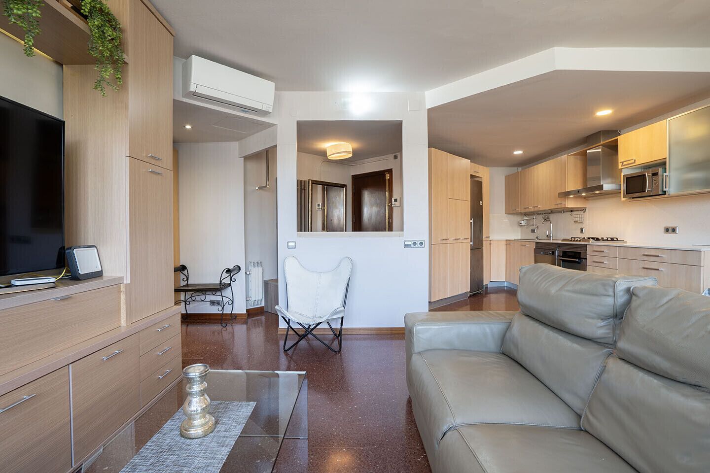Un salon moderne comprenant un canapé, un téléviseur et un coin repas avec une table et des chaises.