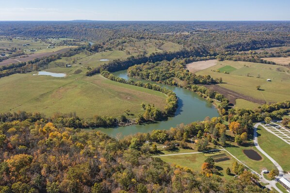 An aerial view of a rural landscape with a river, fields, and scattered buildings.