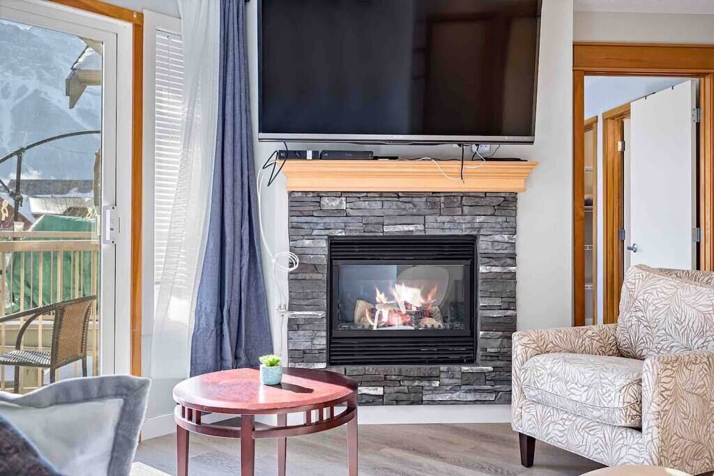 Ein Wohnzimmer mit Kamin, einem darüber montierten Fernseher und einer Couch.