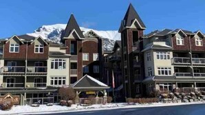 A multi-story hotel with a ski resort backdrop, featuring a mix of traditional and modern architectural styles. - Lux 2BR/5BD Suite/Mountain View! (Canmore)