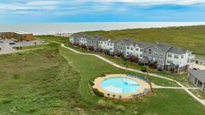 A coastal hotel with a swimming pool, multiple-story buildings, and a beach view.