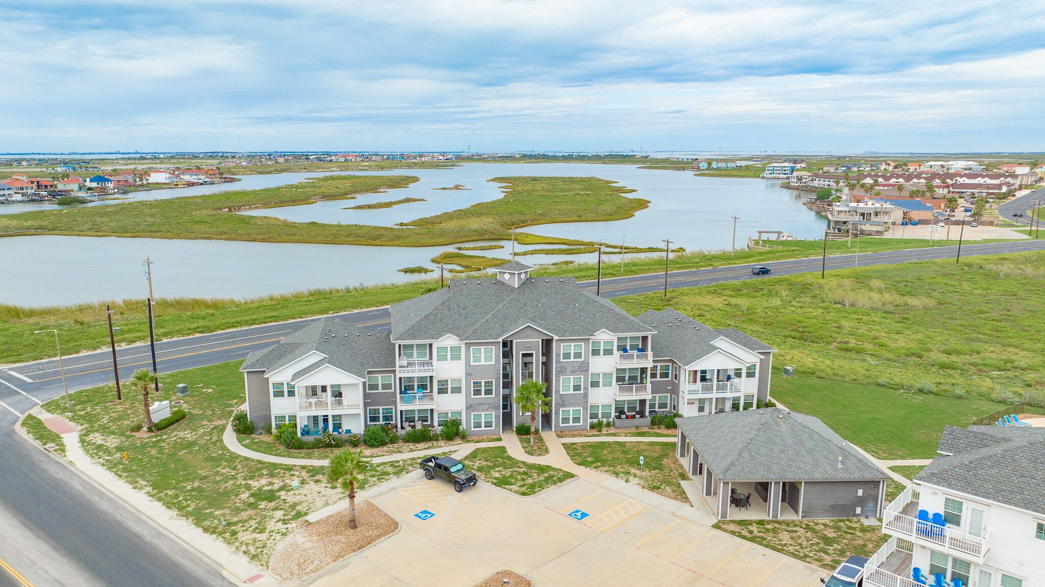 A multi-story hotel with a parking lot, a road, and a river in the background.