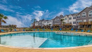 A swimming pool with lounge chairs, surrounded by multi-story buildings with balconies.