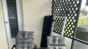 Deux fauteuils inclinables avec coussins, un paravent ajouré et une porte avec une fenêtre.