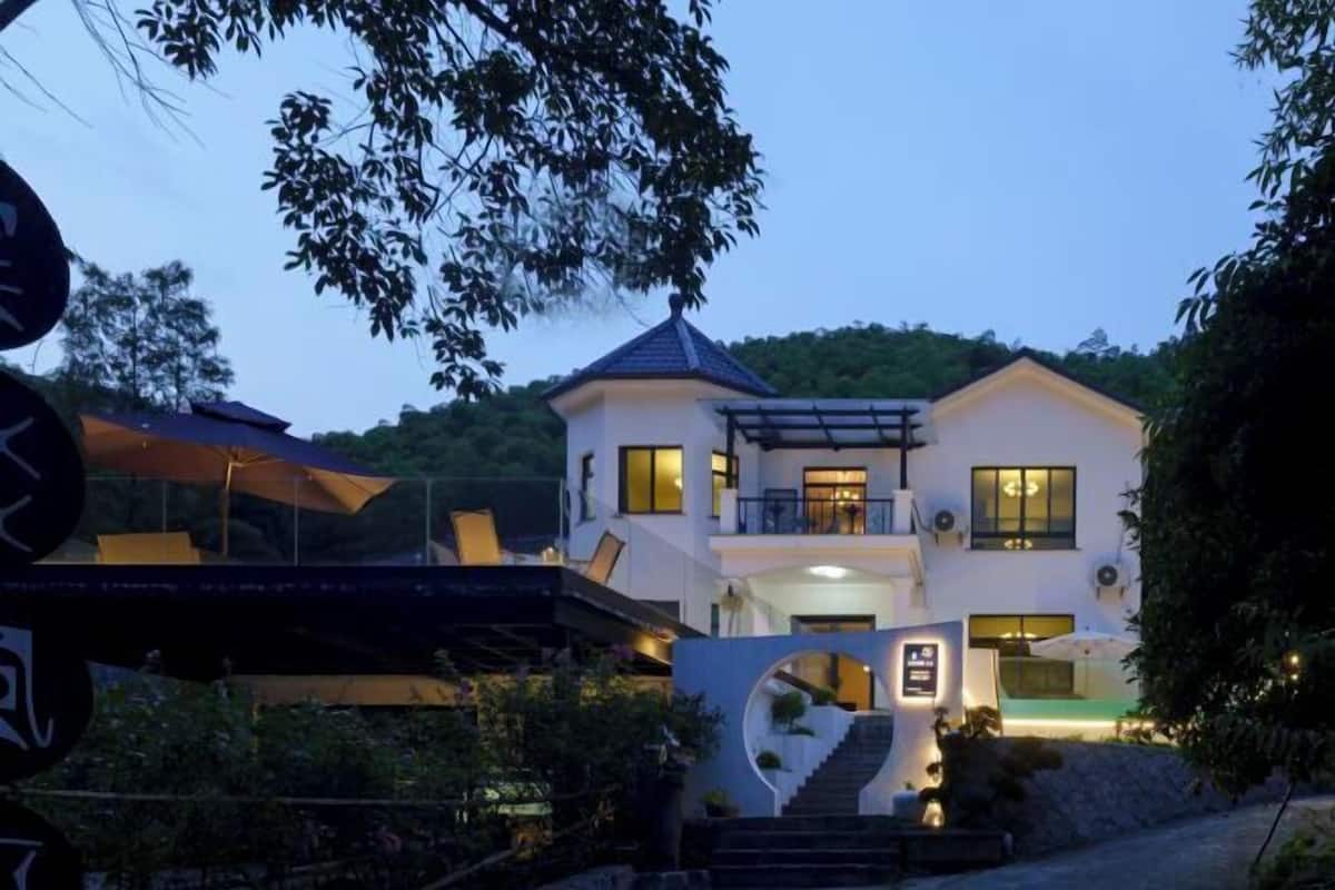 A two-story house with a balcony, a staircase leading to the entrance, and a well-lit exterior.