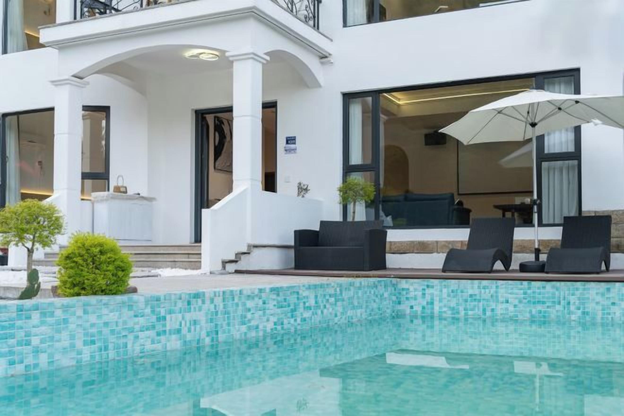 Un hotel moderno con piscina, mobiliario exterior y un patio cubierto.