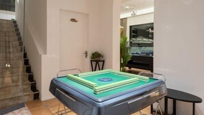 Une table de billard dans une pièce avec un escalier et une porte.