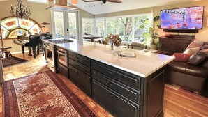A spacious kitchen with a large island, modern pendant lights, and a ceiling fan.
