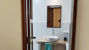 A bathroom with a white sink, a mirror, and a towel hanging on the door. - APU TACLLO LODGE (Layo)