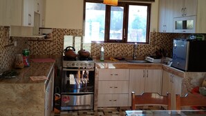 A kitchen with a tiled floor, wooden cabinets, a stove, and a refrigerator. - APU TACLLO LODGE (Layo)