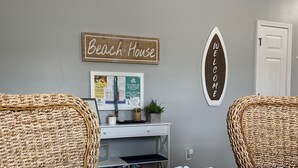 A room with wicker furniture, a desk with a computer, a 'Beach House' sign, and a 'Welcome' sign. - Premier Golf Location - Barefoot Resort! Family/dog friendly - 2 pools/beach! (North Myrtle Beach)