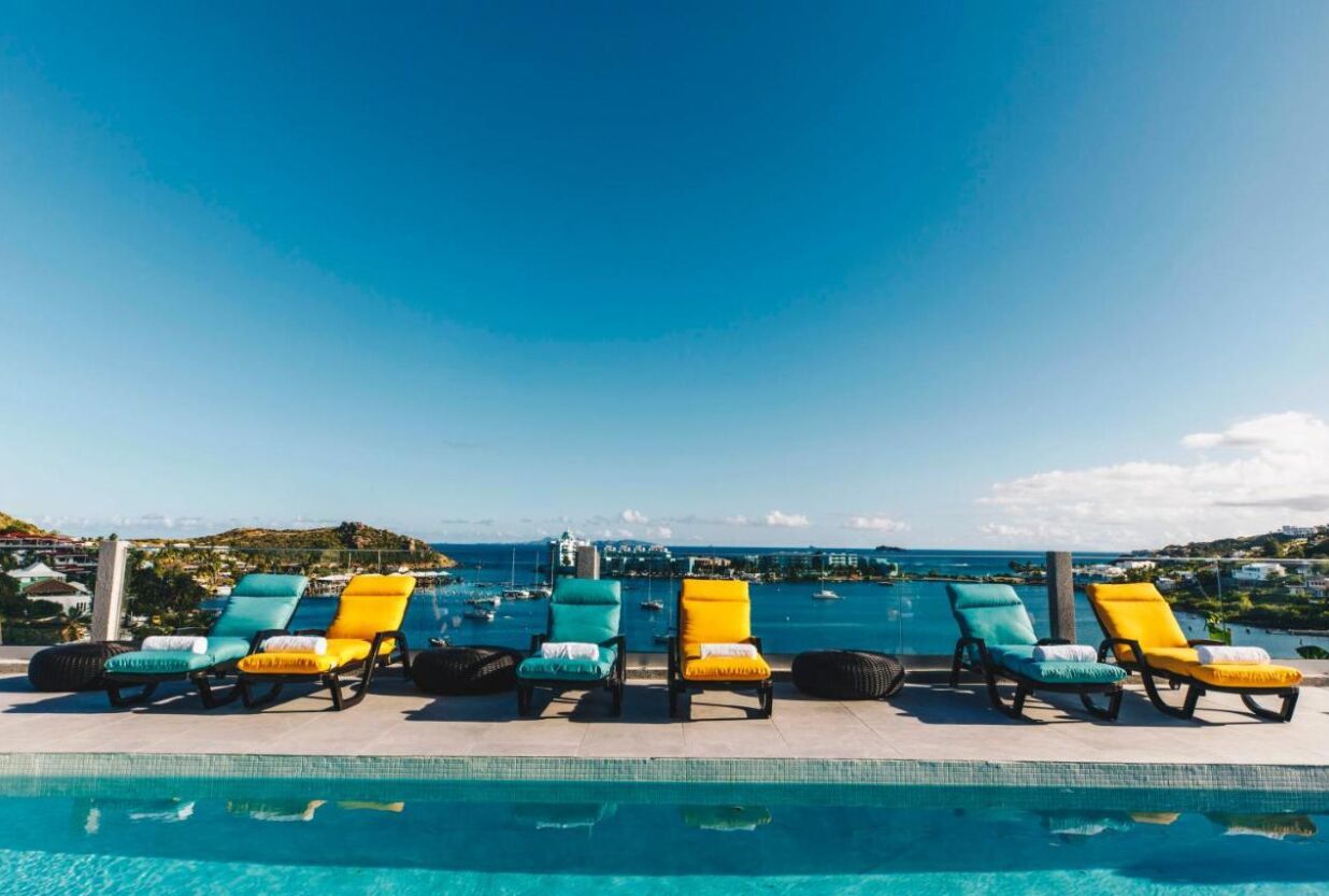 Zona junto a la piscina con sillas de descanso y vista al océano.